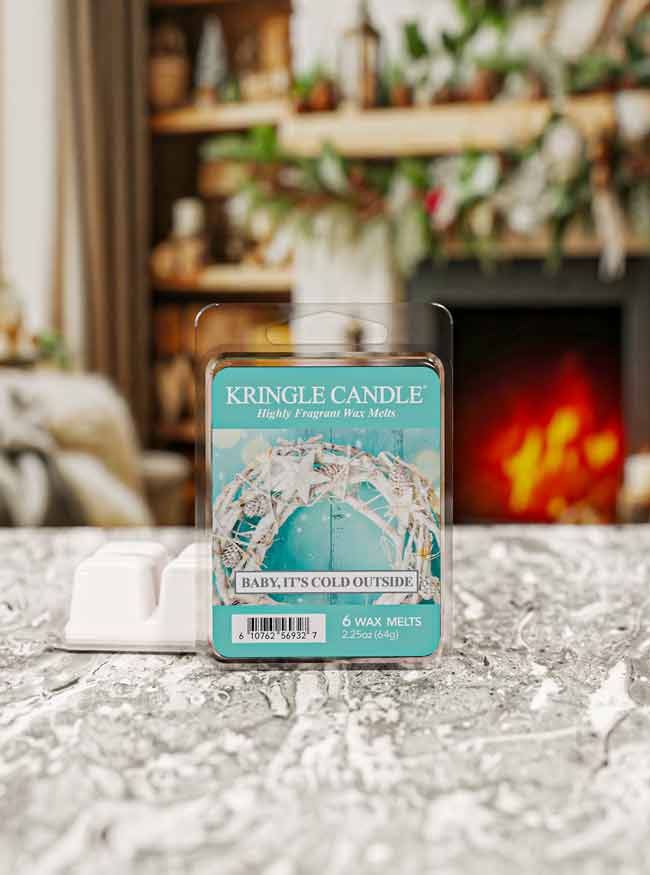 Kringle Candle wax melt package on a textured surface with a blurred fireplace background